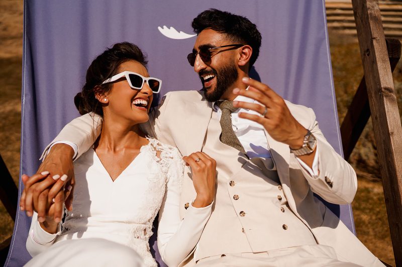 Bride and groom laughing together and wearing sunglasses at a summer wedding - incredible wedding portraits by Oben Studio®
